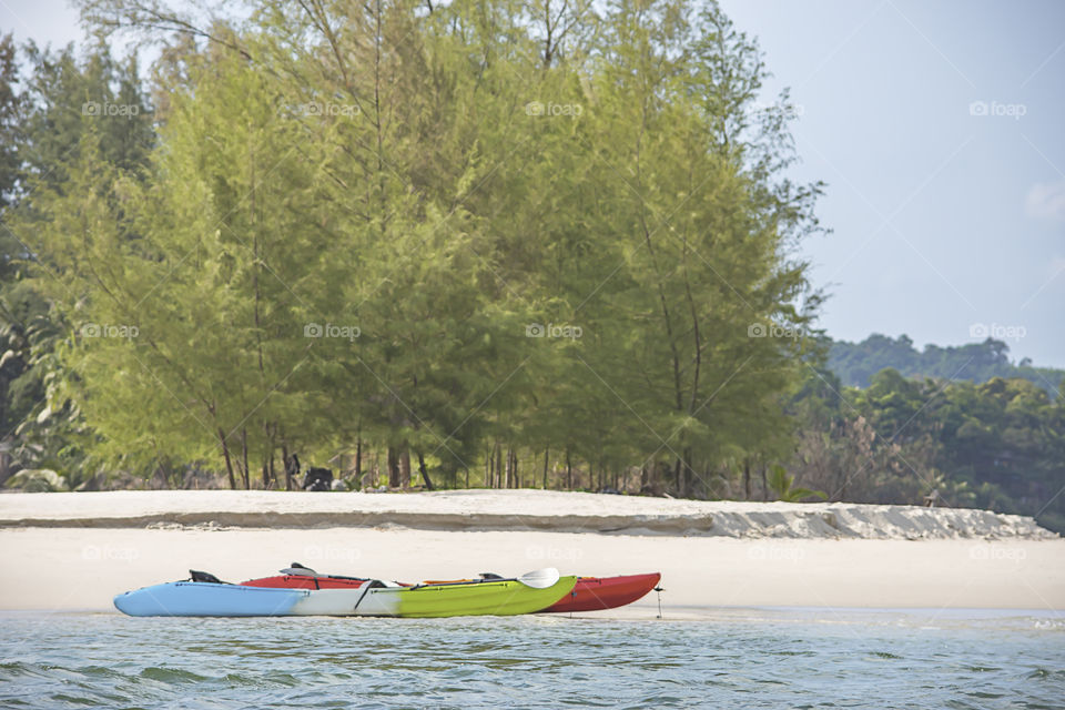 Kayaking on the sand of the sea background trees.