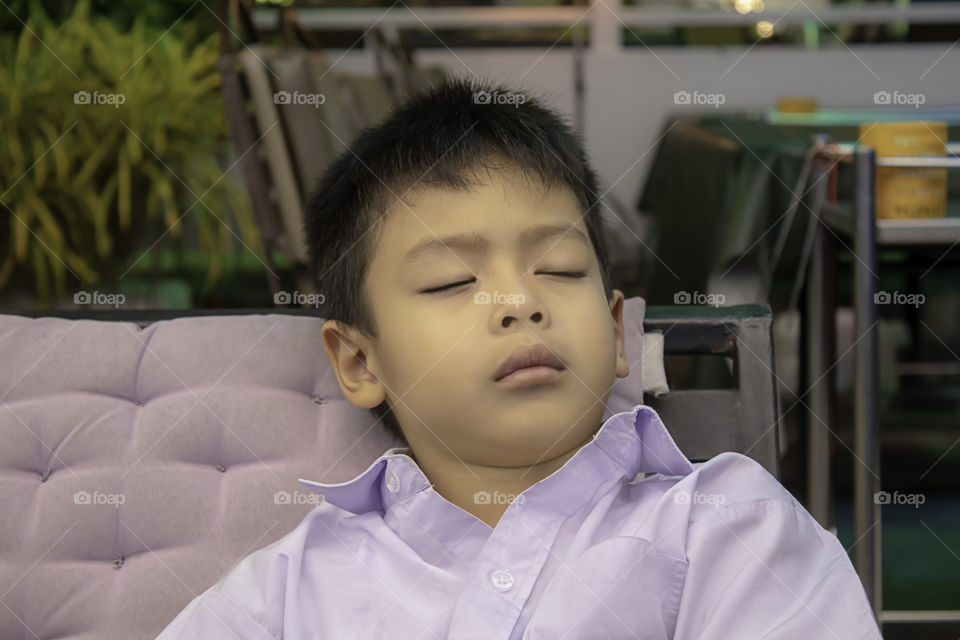 Boys wear white shirts sleeping on a cushion.