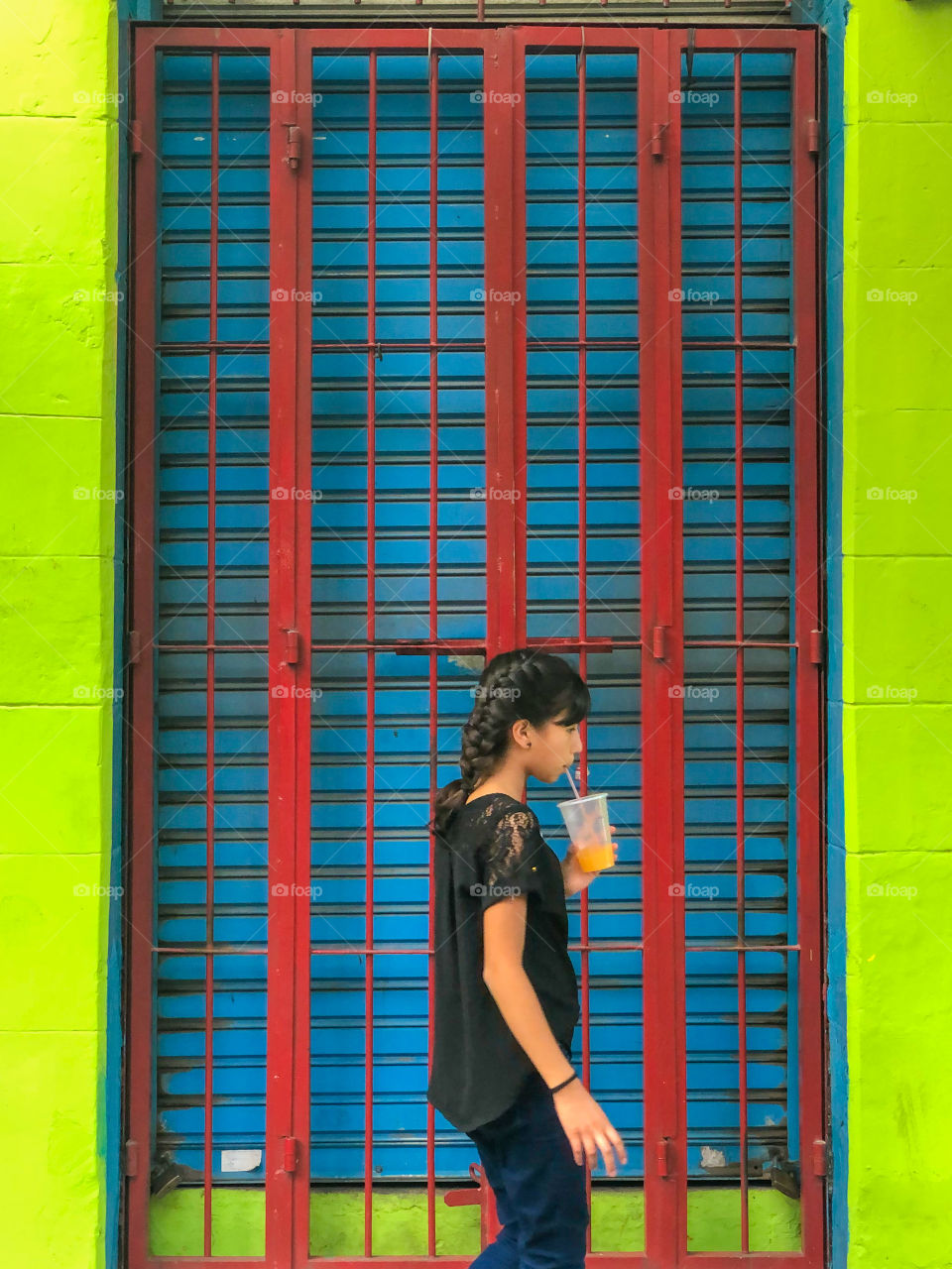 Girl divining juice in a Colorful wall 