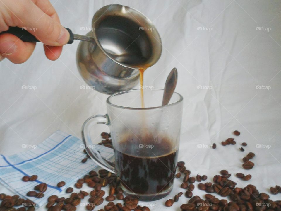 In a cup of coffee poured on the background of coffee beans