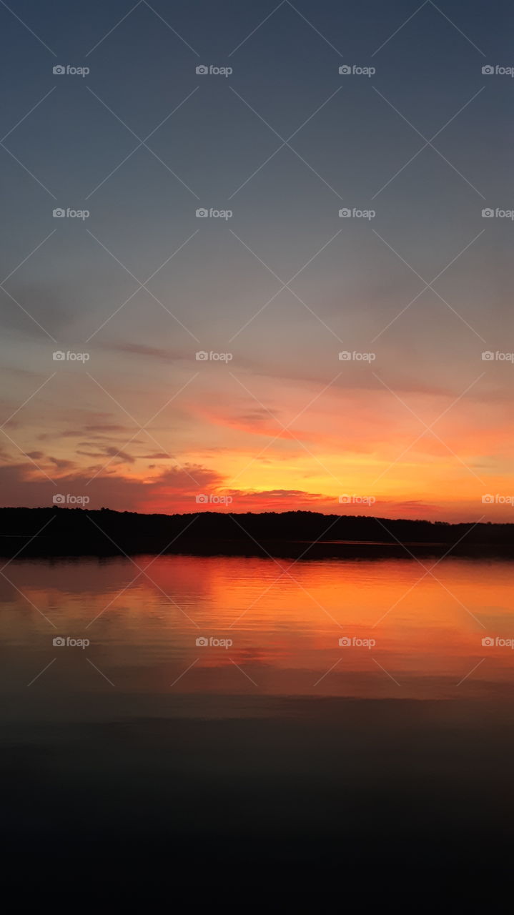 Bright warm red glow of the sun rising over the water