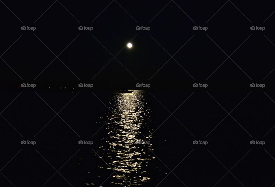 full moon light clearing the sea and a boat