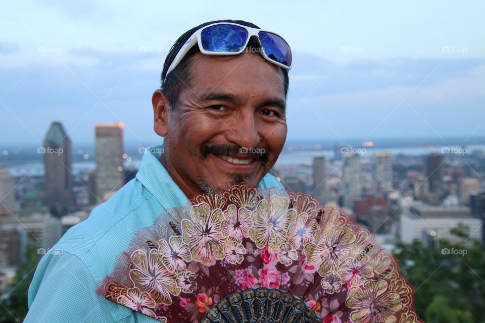 Man with a hand fan is smiling