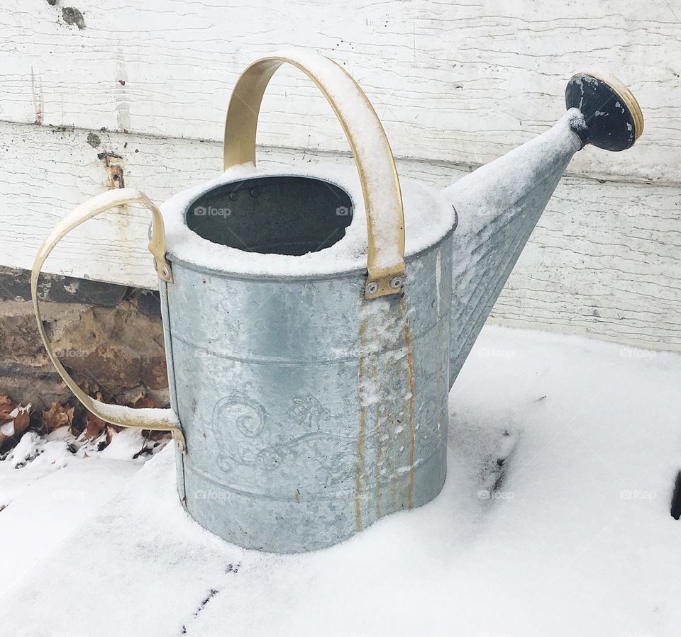 Snowy watering can on the front porch