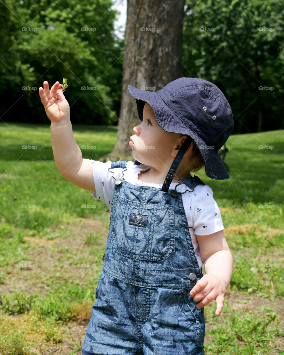 Baby boy looking at flower