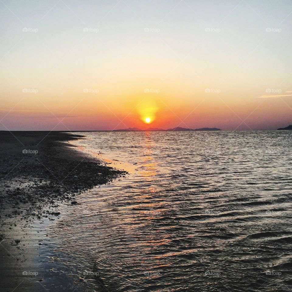 Scenic view of seashore against sunset sky