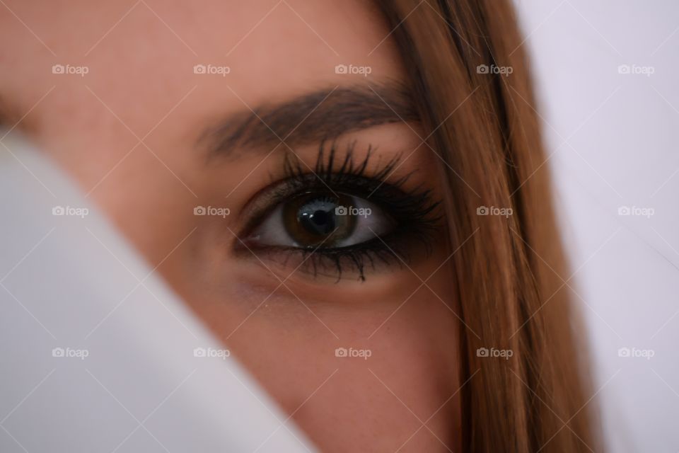 face of a woman hidden behind, eyes looking at you