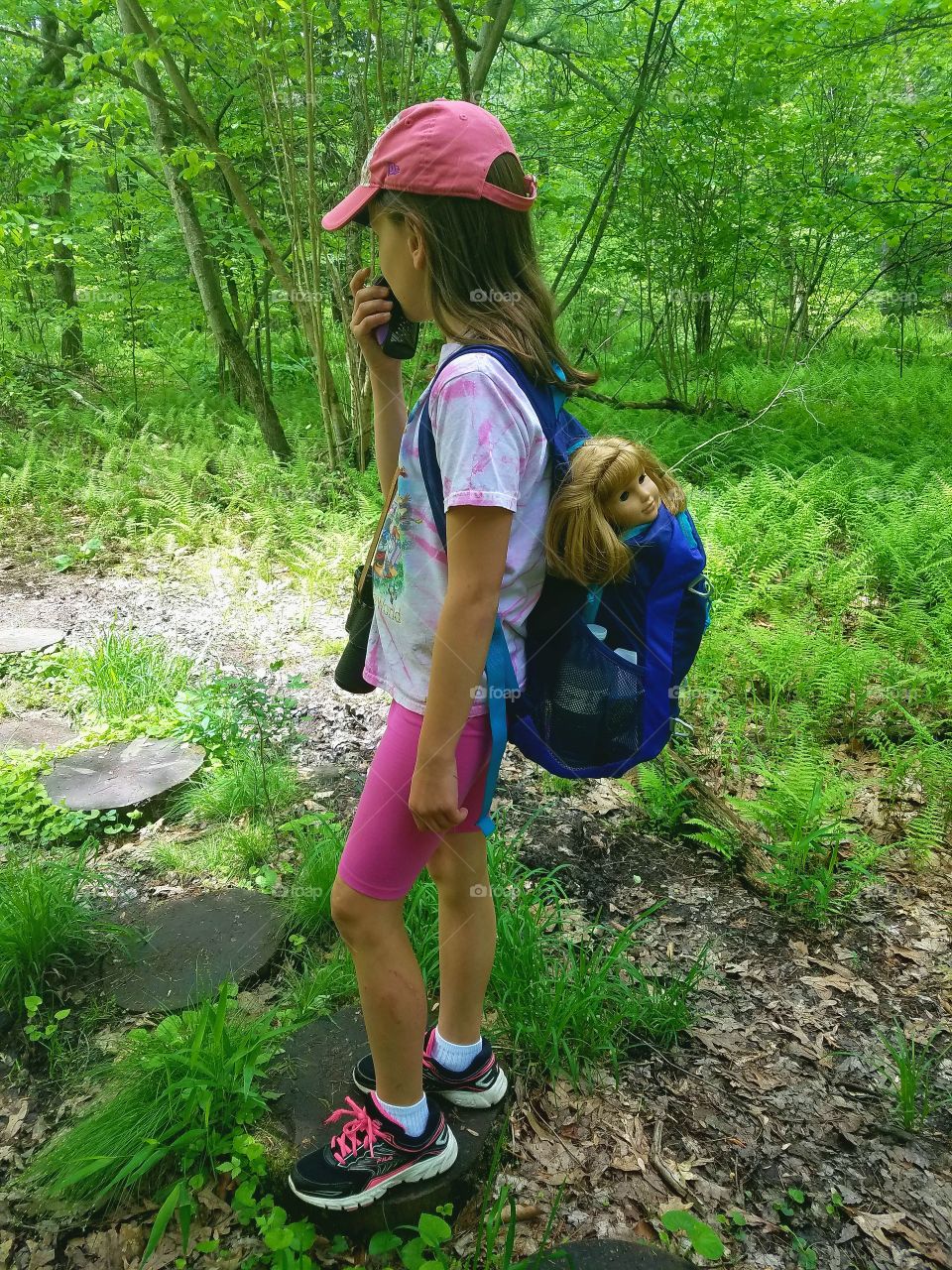 girl hiking with doll in backpack, binoculars, walkie-talkie