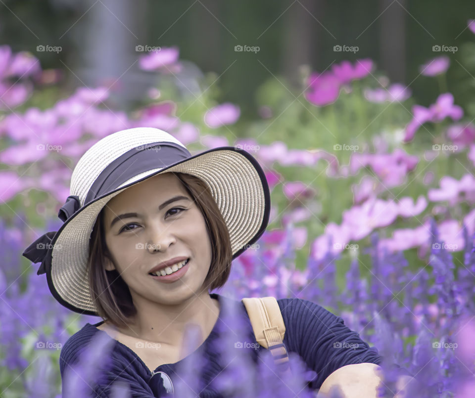 Portrait of Asean woman wearing a hat in the flower garden.