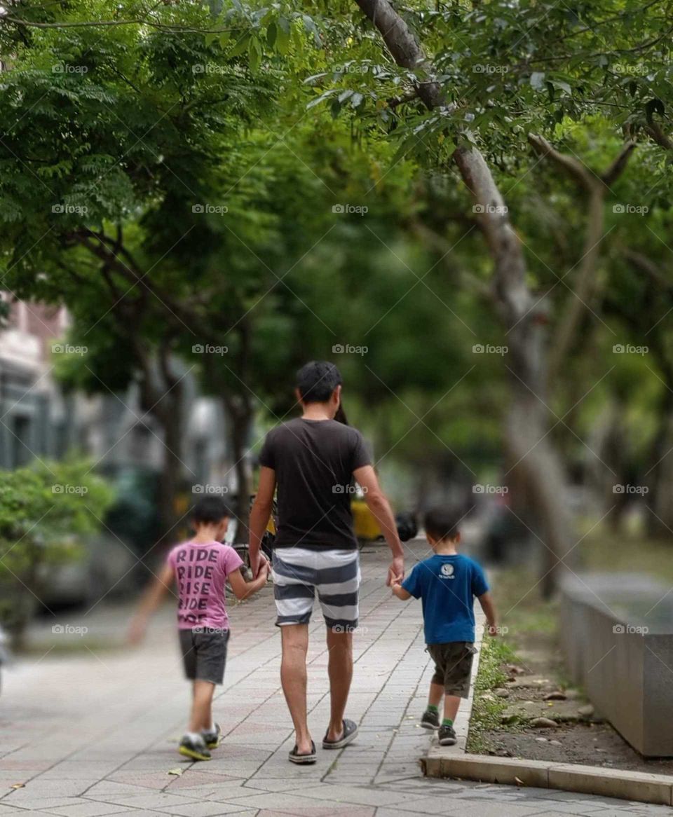 staying in good shape: a father with two sons walking in the park, a sense of the warm family.