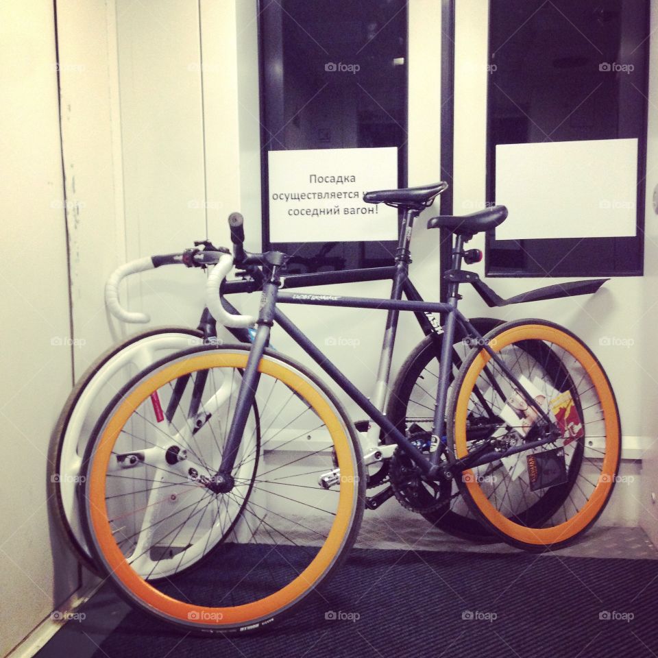 Grey brakeless fixie bike with orange wheels and cinelli fixie standing in the train