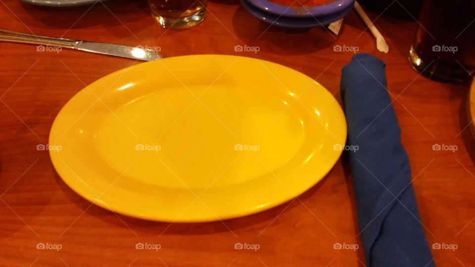 Yellow plate at Mexican Restaurant with blue napkin rolled flatware