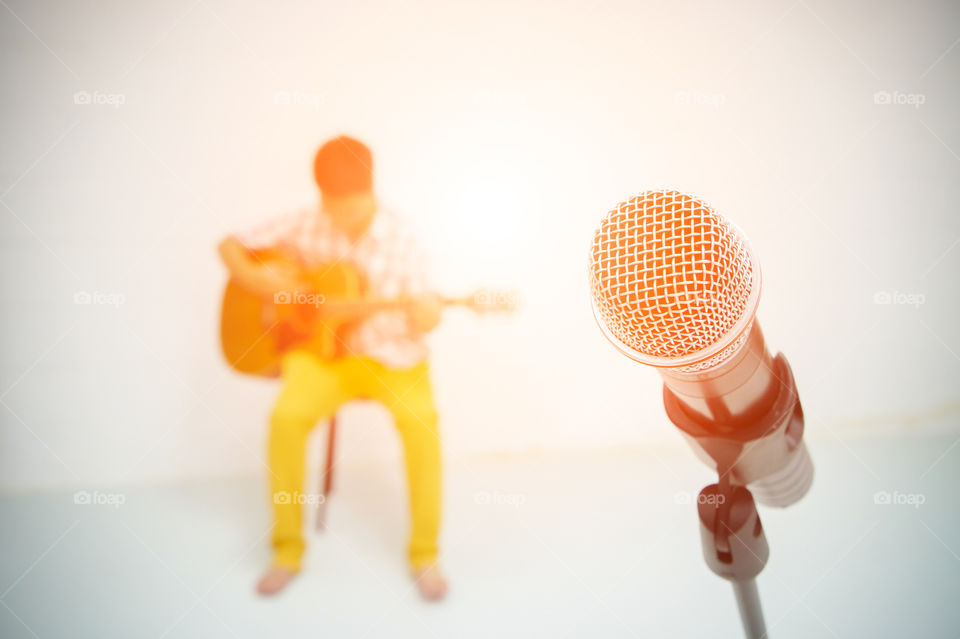 A microphone and blurred man playing guitar