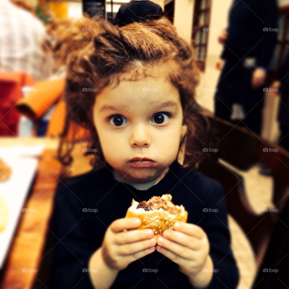 Little girl eating hamburger and surprised