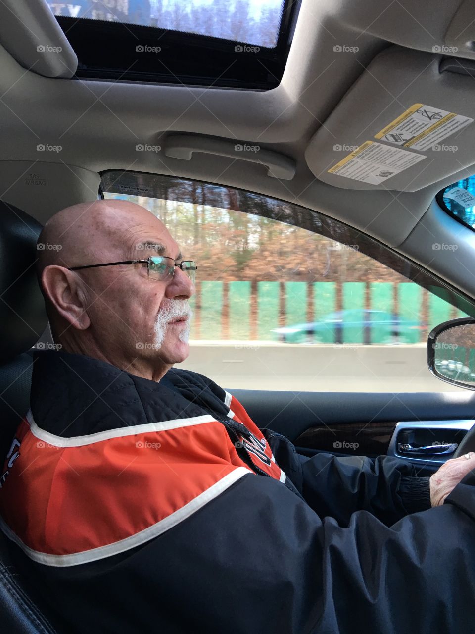 Man driving car, profile photo, looking at the rear view mirror before taking exit. We are going down a divided highway on a sunny day with heavy traffic!