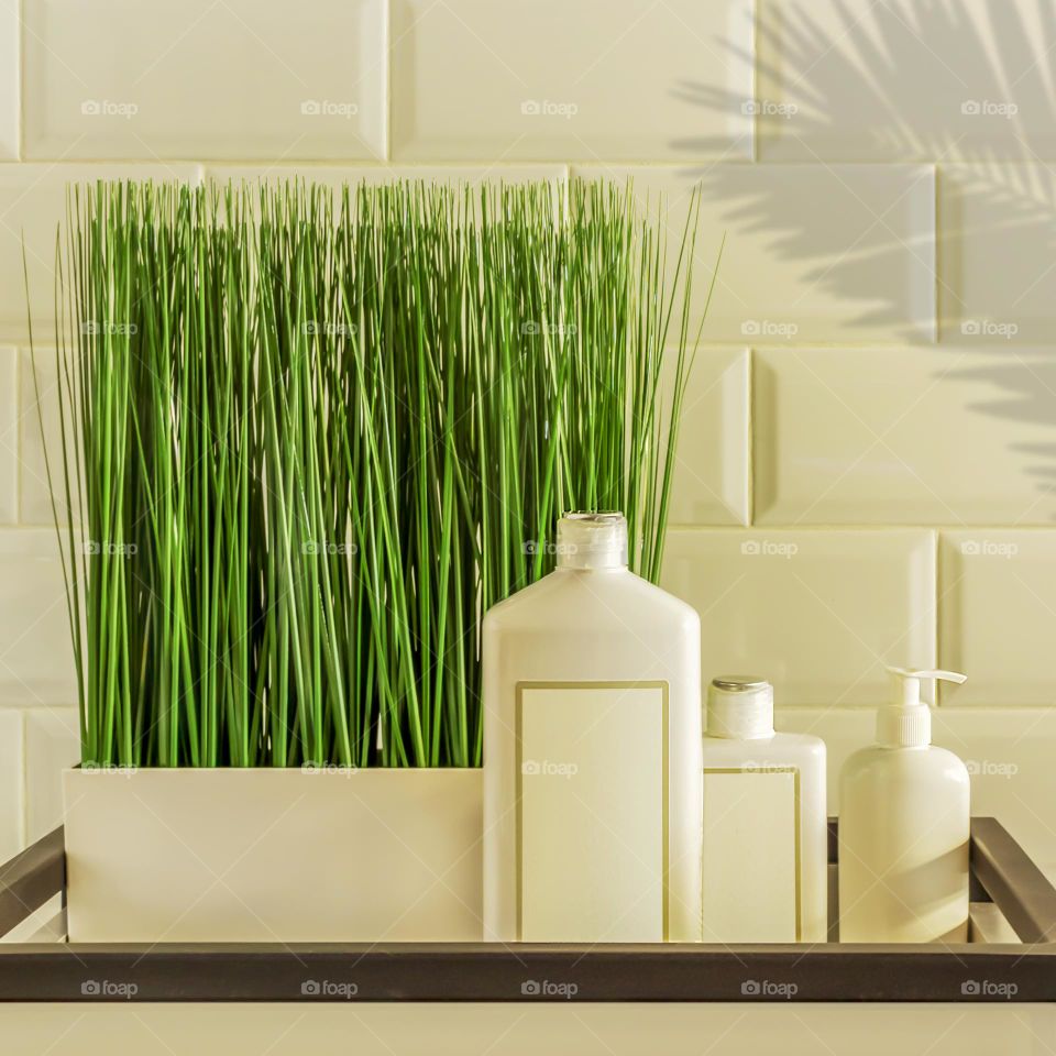 Cosmetics SPA branding mock-up. The concept of using of creating natural, organic cosmetics for body and hair. White cosmetic bottles with a pot of decorative grass on a shelf on a white background