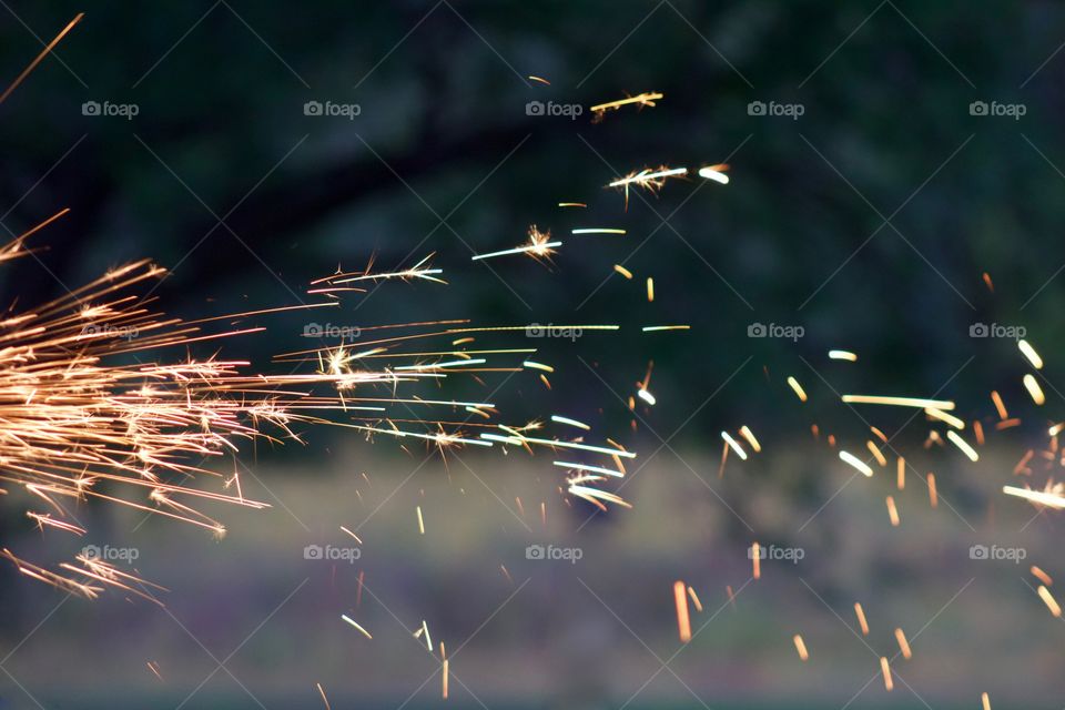 Side view of sparks from a bench grinder being used on a steel part