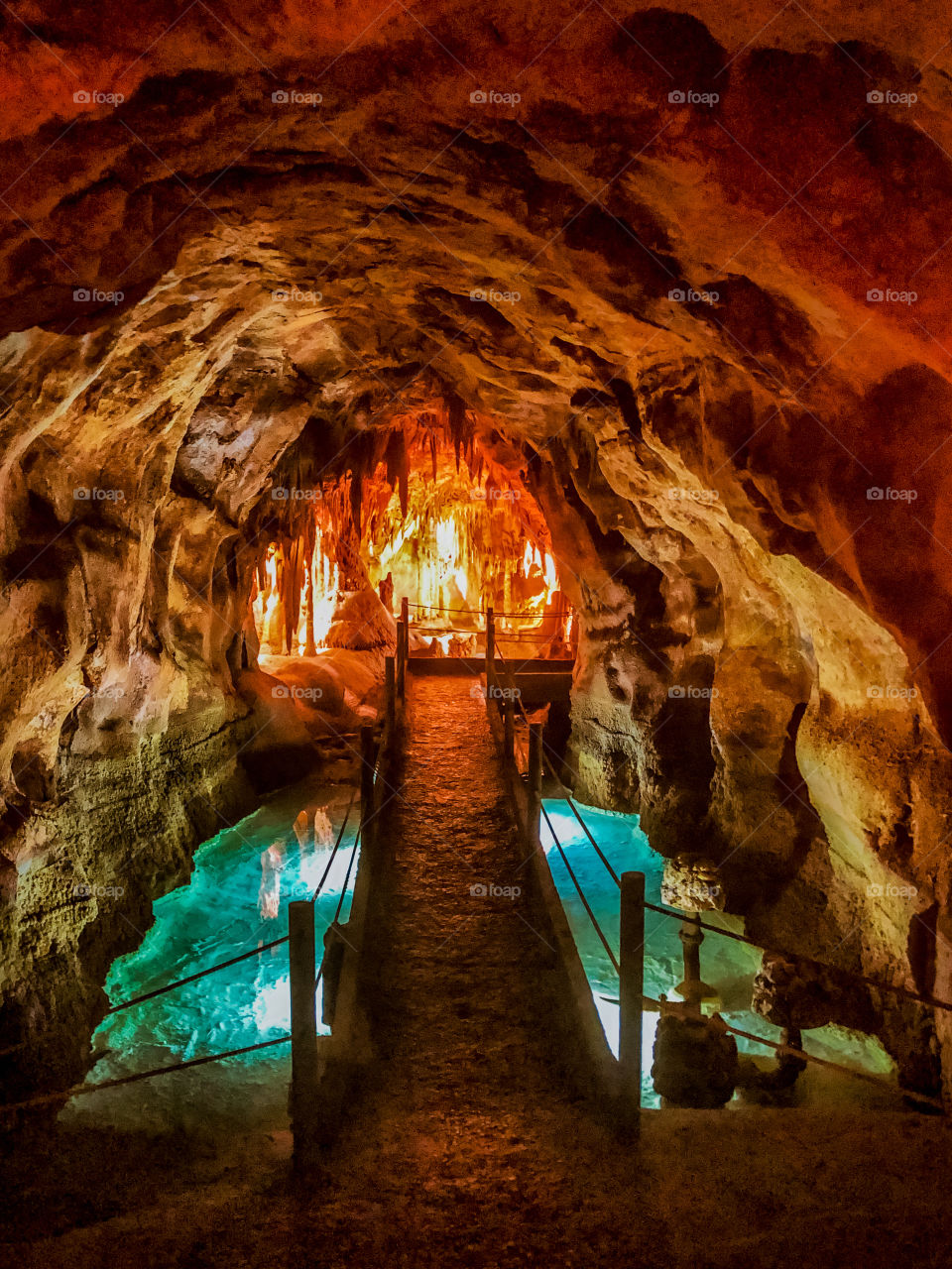 A bridge across the rock pool leads to a fiery looking cavern, Grutas de Alvados - Central Portugal- 2019