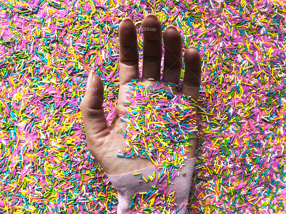 Female hand covered by colorful sprinkles 