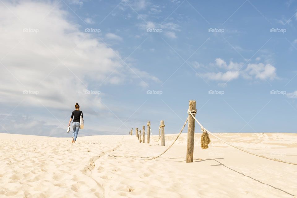 Barefoot woman walking on sand dunes during summer holiday
