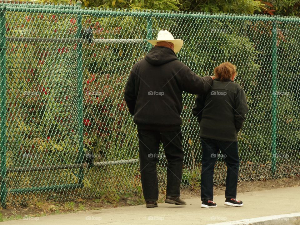 Old Married Couple Walking On The Sidewalk