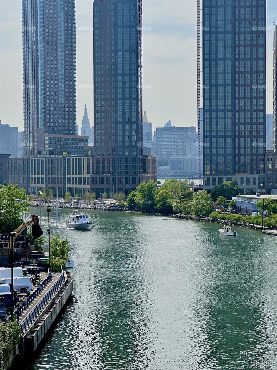 This is “Newtown Creek” seen from the “Pulaski Bridge” that connects “Greenpoint”, Brooklyn to LIC, Queens. Across the “East River” we see parts of “Manhattan” zoomed in on the “New York Life Building” with the golden roof. 2024. Hypnotic Productions