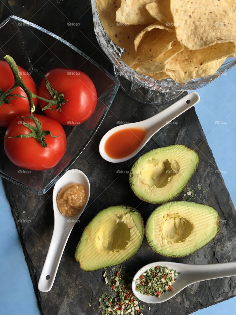 Healthy vegetables for spring time cooking at home. Tomatoes, avocado and spices for the perfect guacamole.