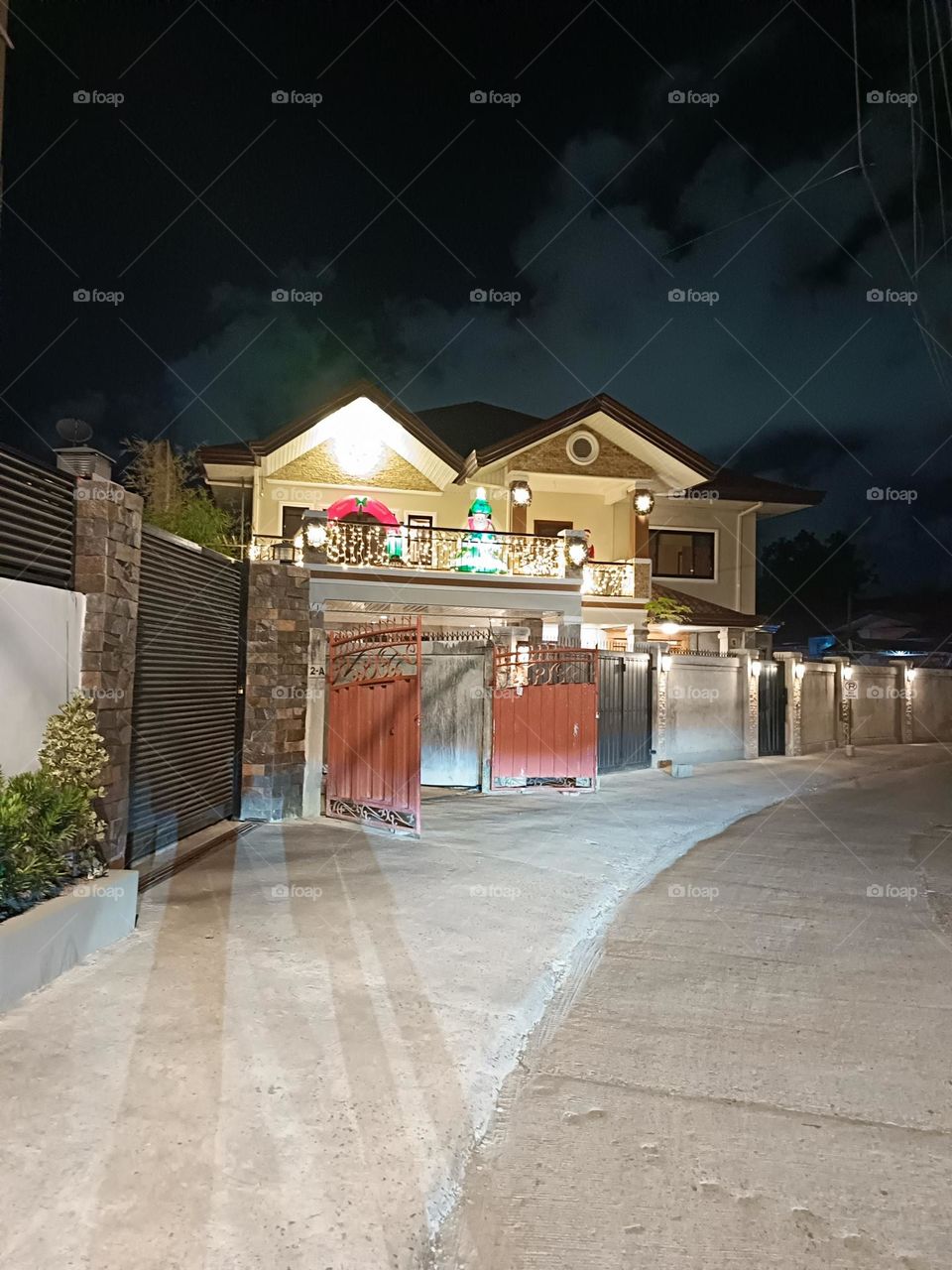 "Under the vast, quiet night sky, this home stands as a warm beacon of festivity and comfort, its soft lights casting a gentle glow that spills onto the street. The holiday decorations add a joyful spirit.