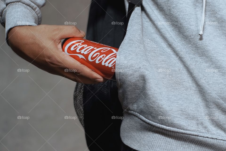 Hands are picking up a Can of Coca Cola
