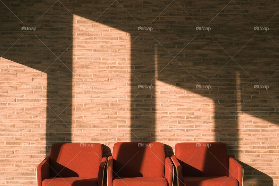 A empty sitting lounge with chairs and light coming through blinds of a lobby