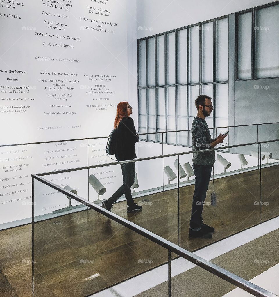 Man and woman near glass railing in modern office