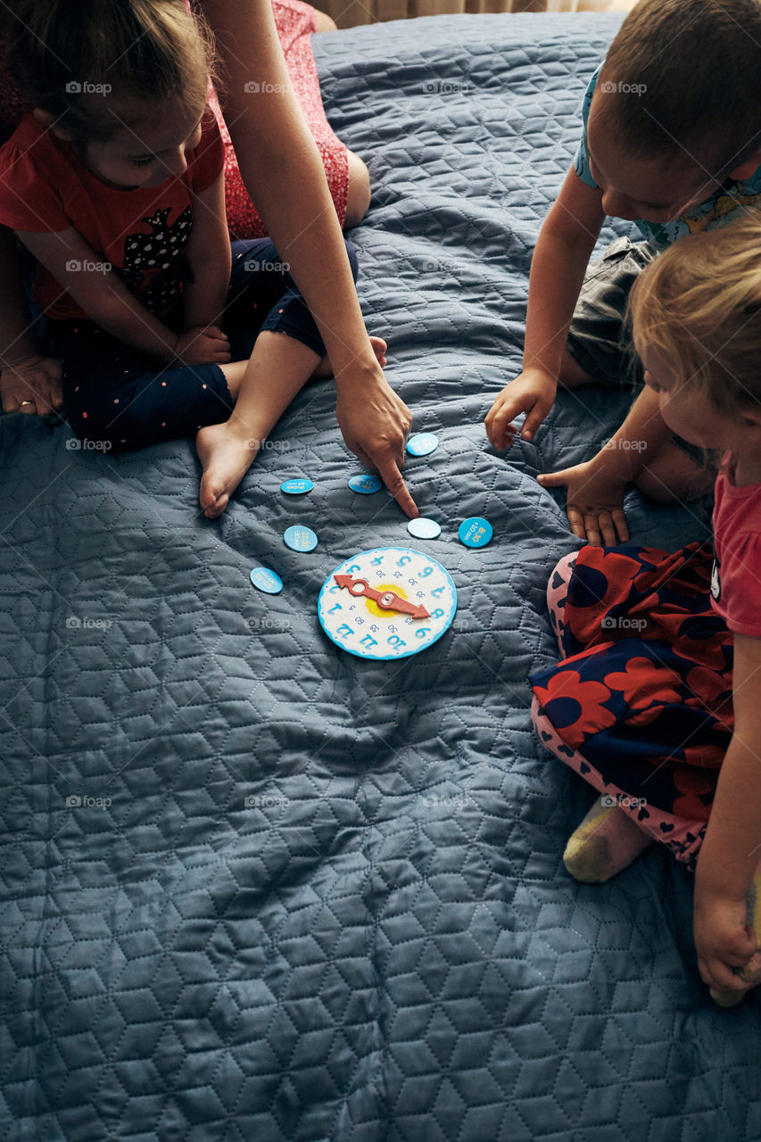 Kids learning how to tell time from clock and set the hands in the correct position. Teaching preschoolers tell time. Candid people, real moments, authentic situations