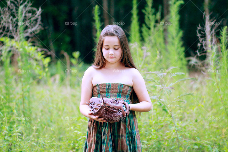 Girl in a dress with her glove and softball