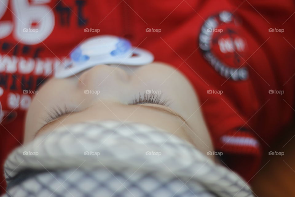 Infant sleeping with soother in his mouth