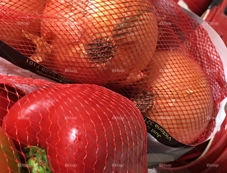 Red sweet capsicum  sweet bell peppers and onions in red nylon mesh bag bright colour closeup vegetable 