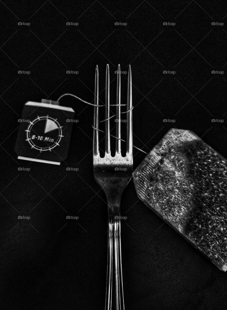 A black and white photo of an ordinary fork with a tea bag on it captured in an unordinary way