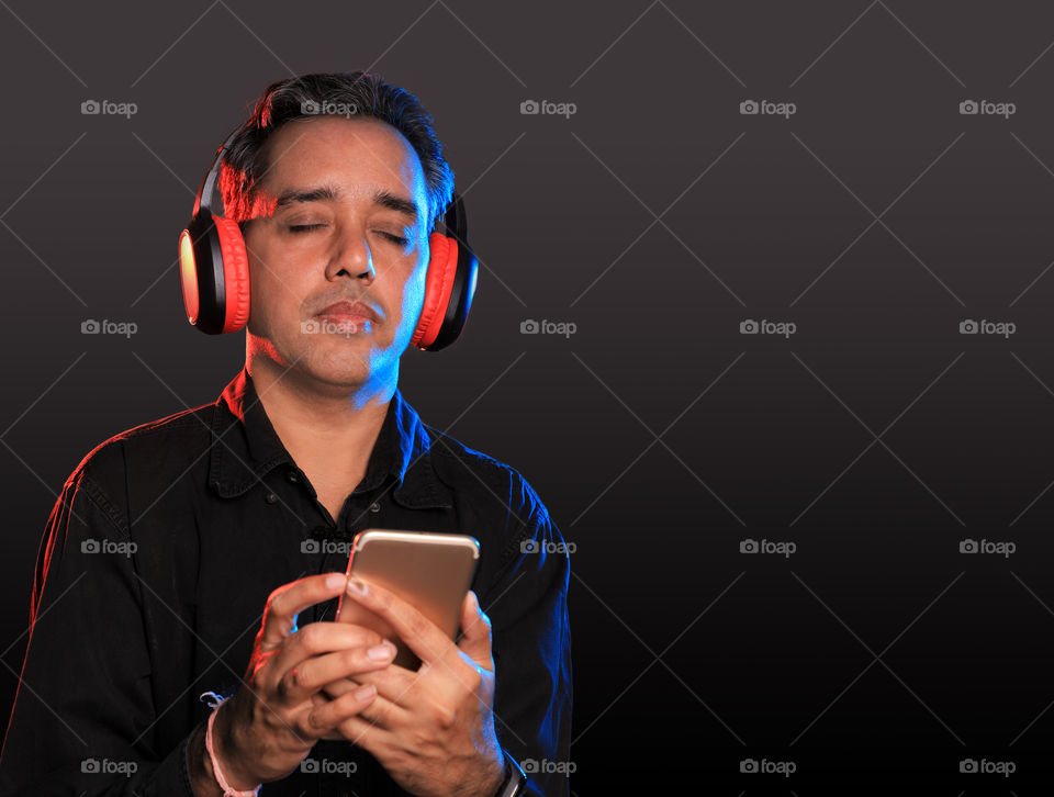 Indian man listening and enjoying music with Bluetooth wireless headphones