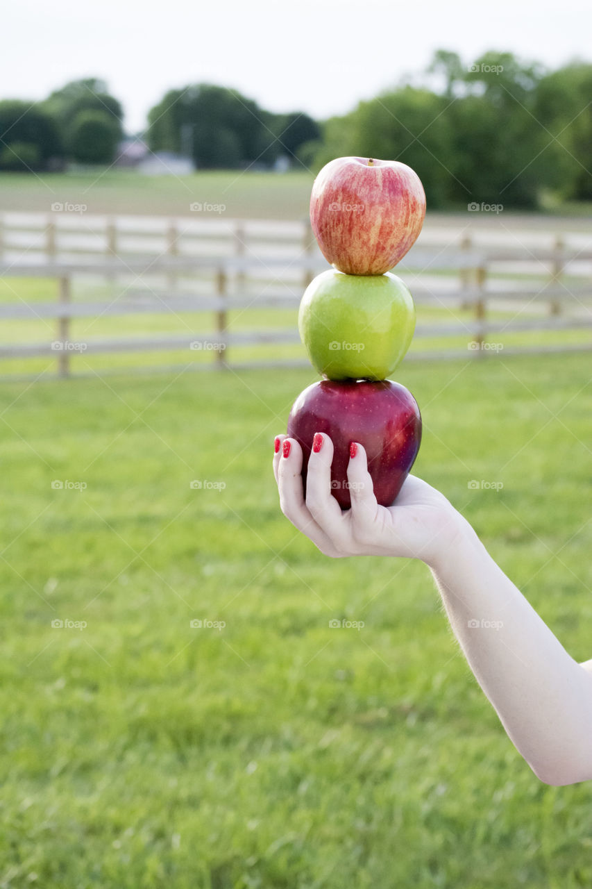 Woman balancing apples outdoors