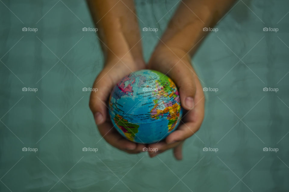 overhead looking down on hands holding world sphere, showing Africa, Europe and America continents