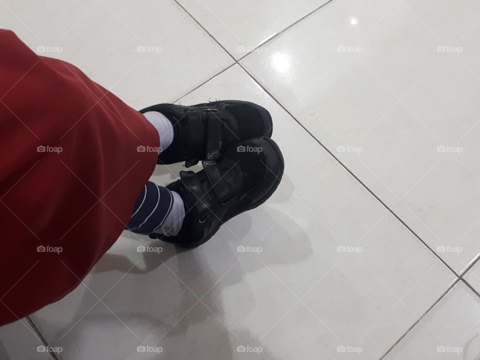 a pair of shoes of a small child waiting in line at an office in the morning at sunny day