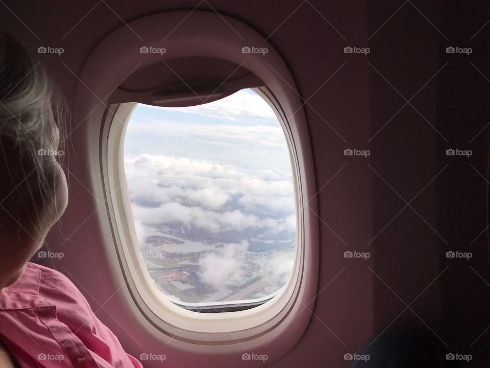 Lovely lady enjoying an areal view through a jetliner’s window.