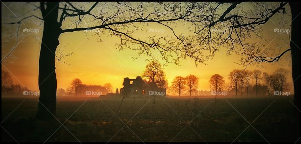 A silhouette of an abandoned building against a setting sun.
