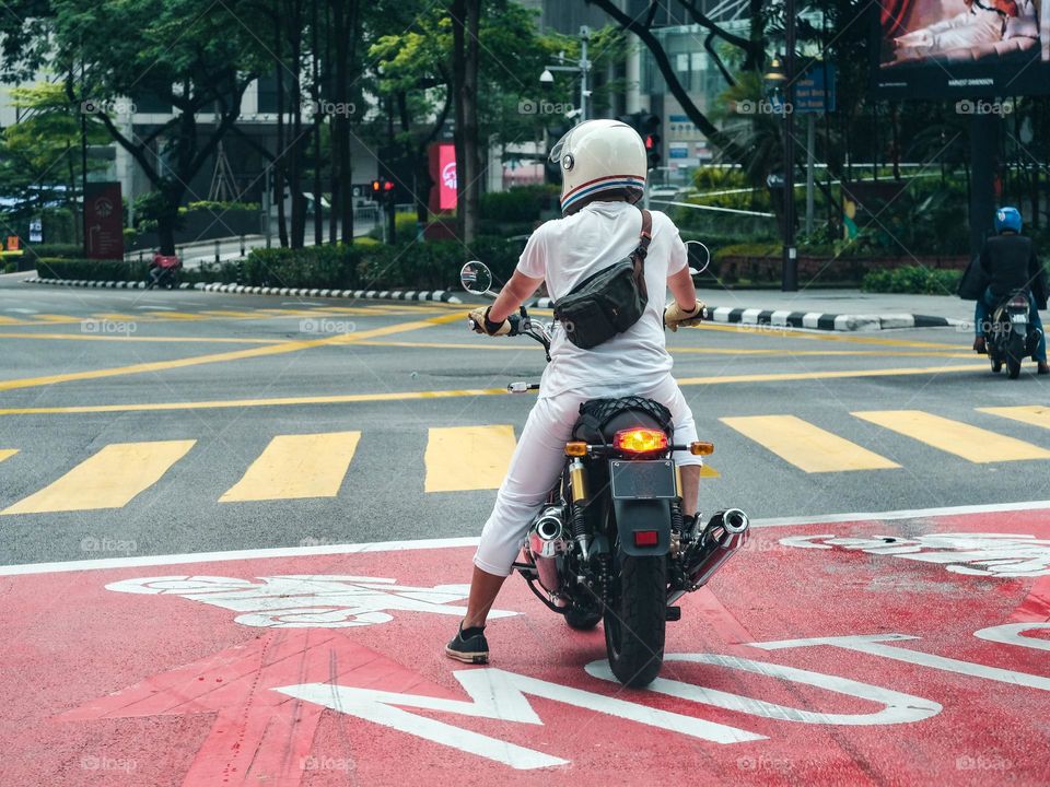 A man on a motorcycle waiting at the traffic light junction in kuala lumpur