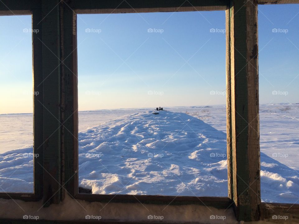 Snow and sky through a window of a capsized ship on the Arctic Ocean 