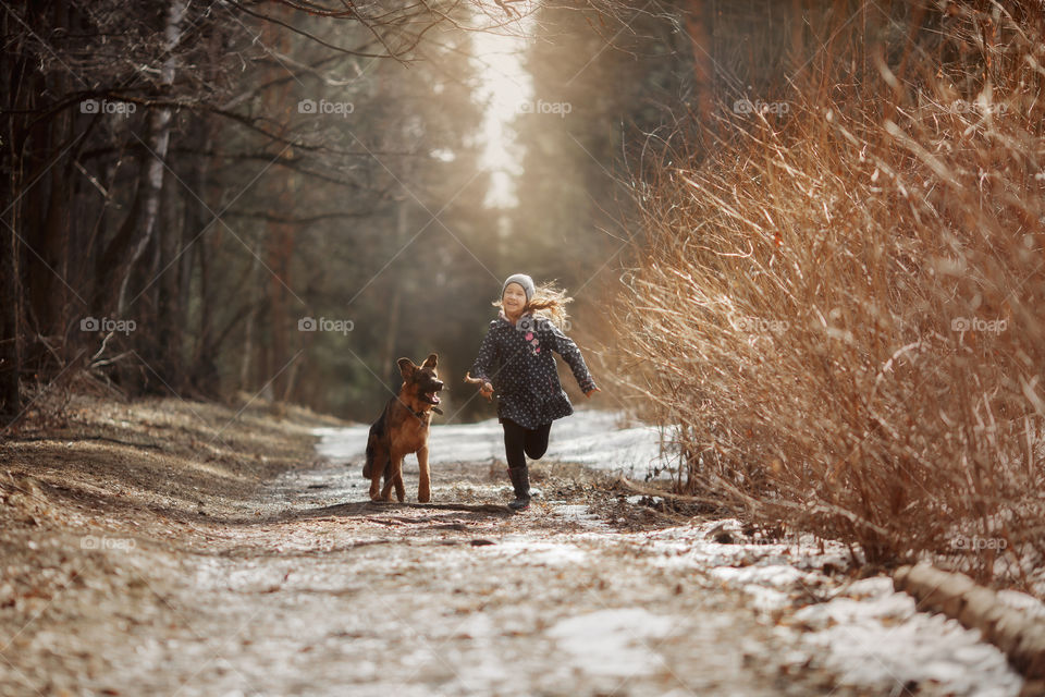 Girl walking with German shepherd puppy in a spring forest 