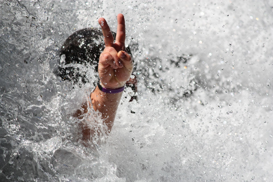 Man showing v sign with splashing water