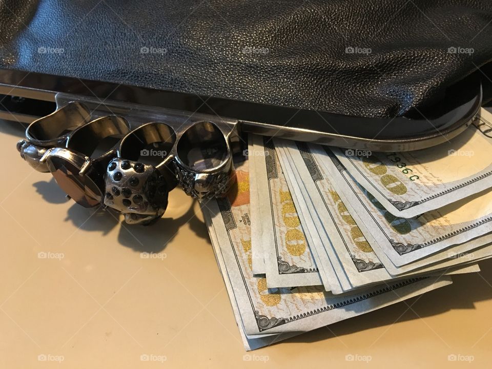 Clutch purse full of paper money, finger grip clasp.
