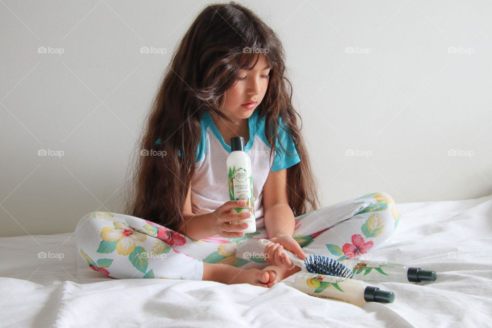 Cute girl with a gorgeous long hair is sitting on a bed