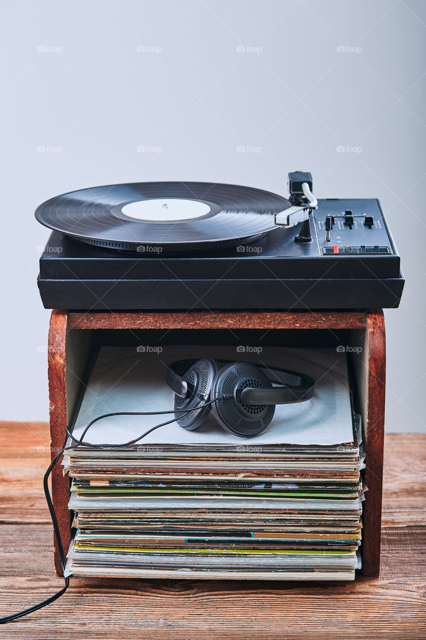 Stack of black vinyl records, turntable vinyl player and headphones. Classic stereo set. Candid people, real moments, authentic situations