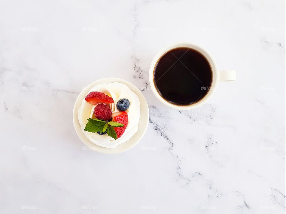 Top view to mug with coffee and pavlova dessert.